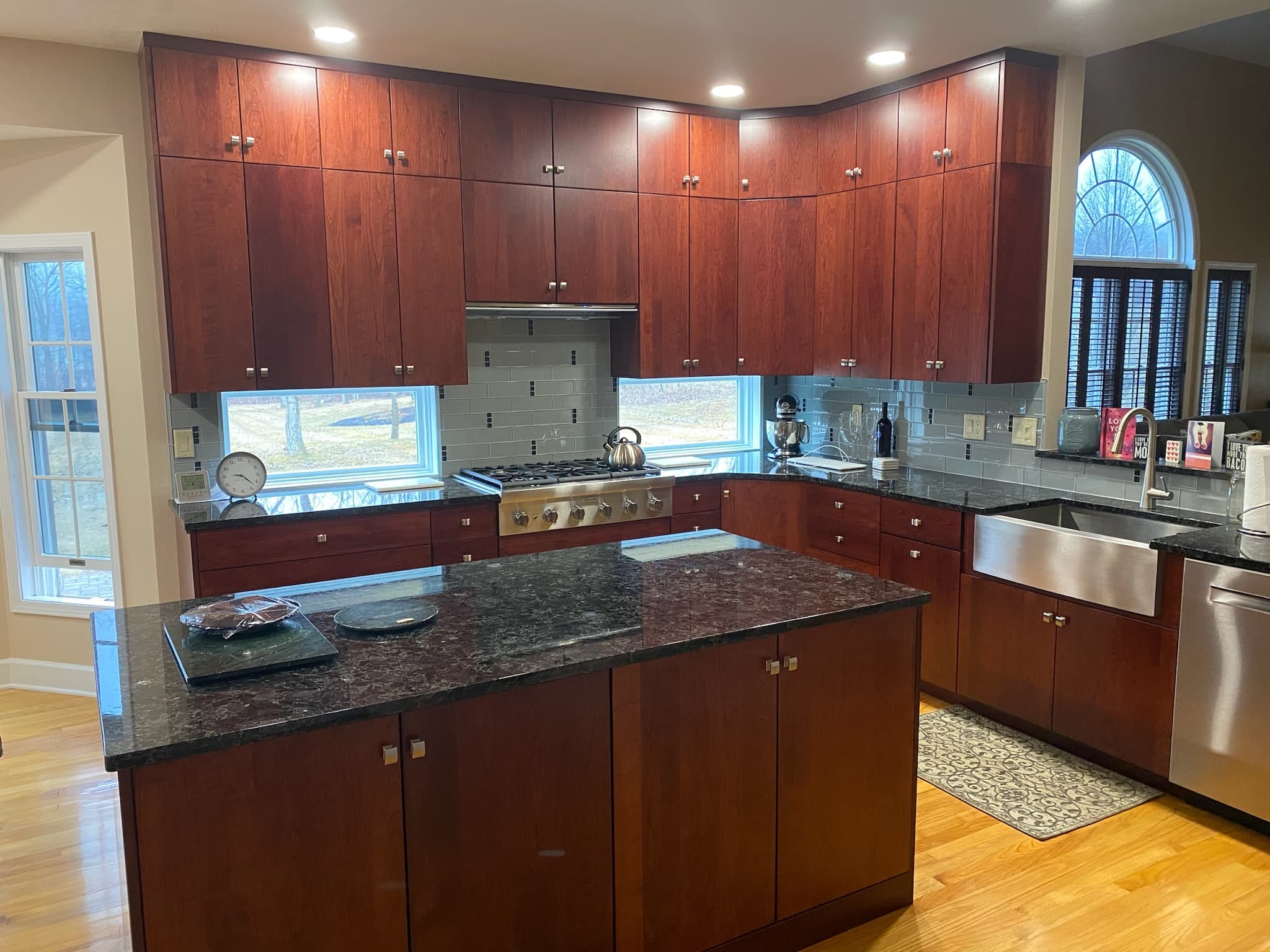 A transitional kitchen features medium wood flat-panel cabinets, dark granite countertops, and a subway tile backsplash