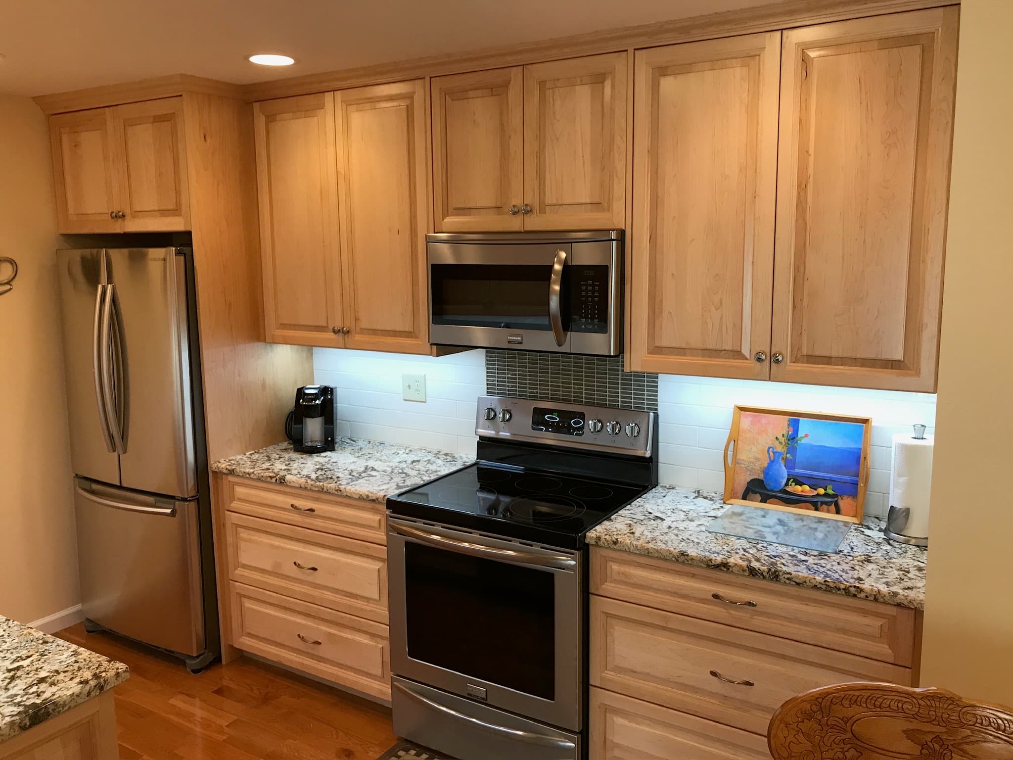 A kitchen featuring light wood recessed panel cabinets, granite countertops, a stainless steel range, and an over-the-range microwave