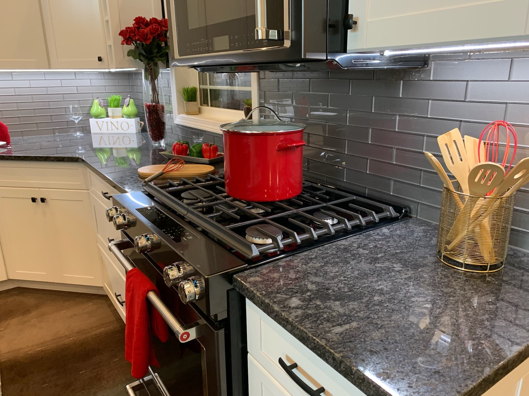 White shaker cabinets and dark granite countertops frame a gas range with an oven in this transitional kitchen