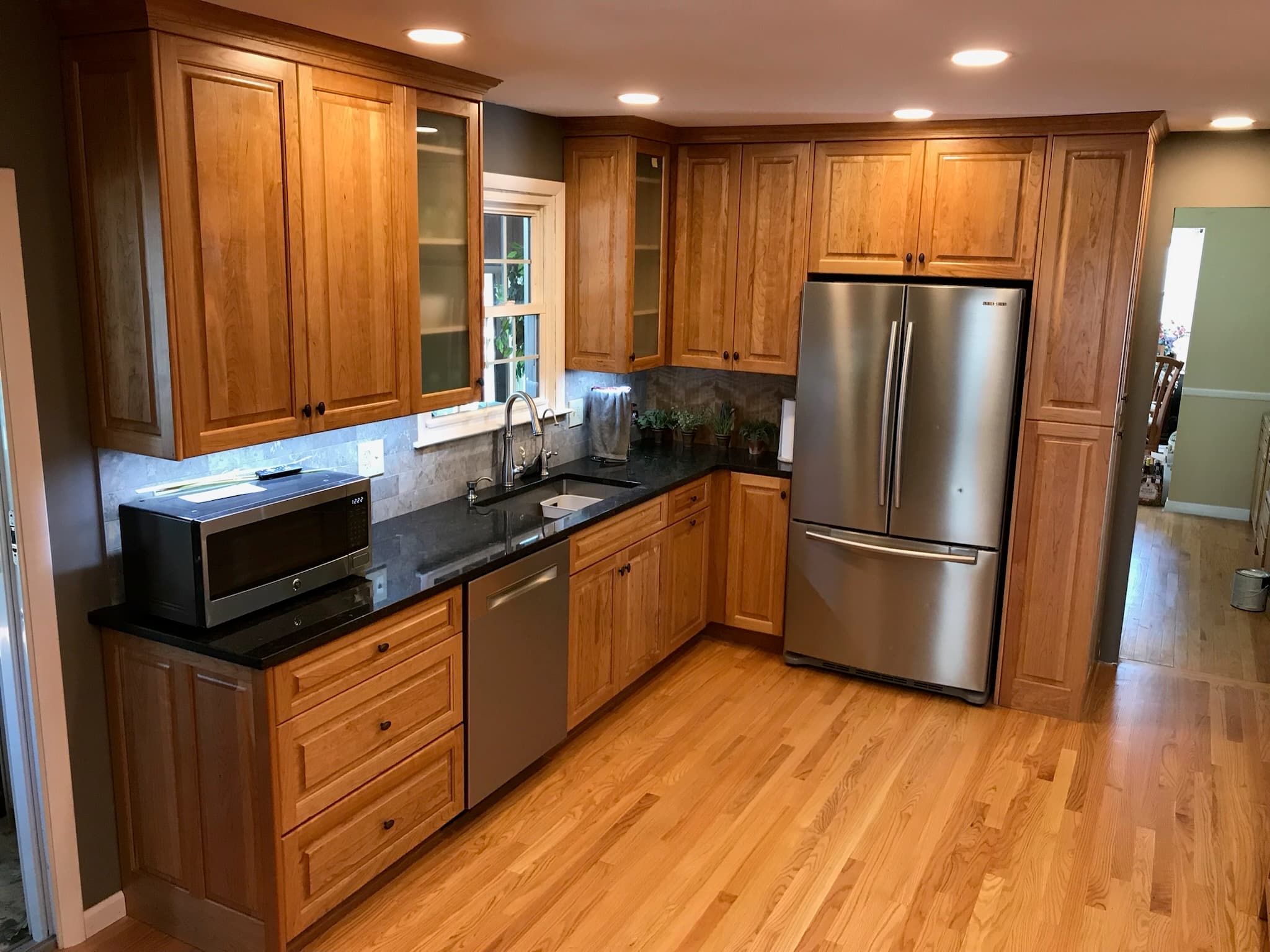 A transitional kitchen features medium wood cabinets, black granite countertops, and stainless steel appliances