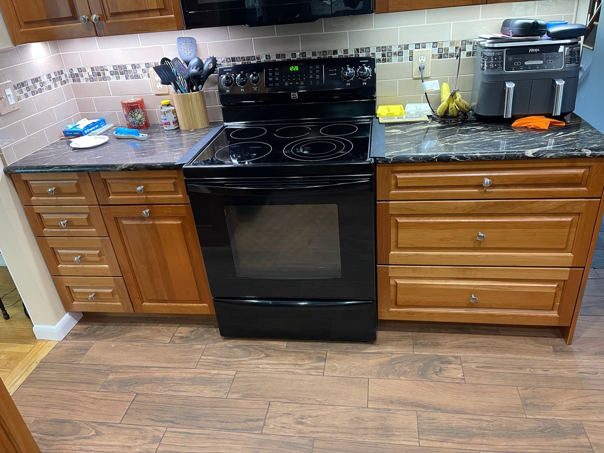 Traditional kitchen with medium wood raised panel cabinets, dark granite countertops, and a black range and microwave
