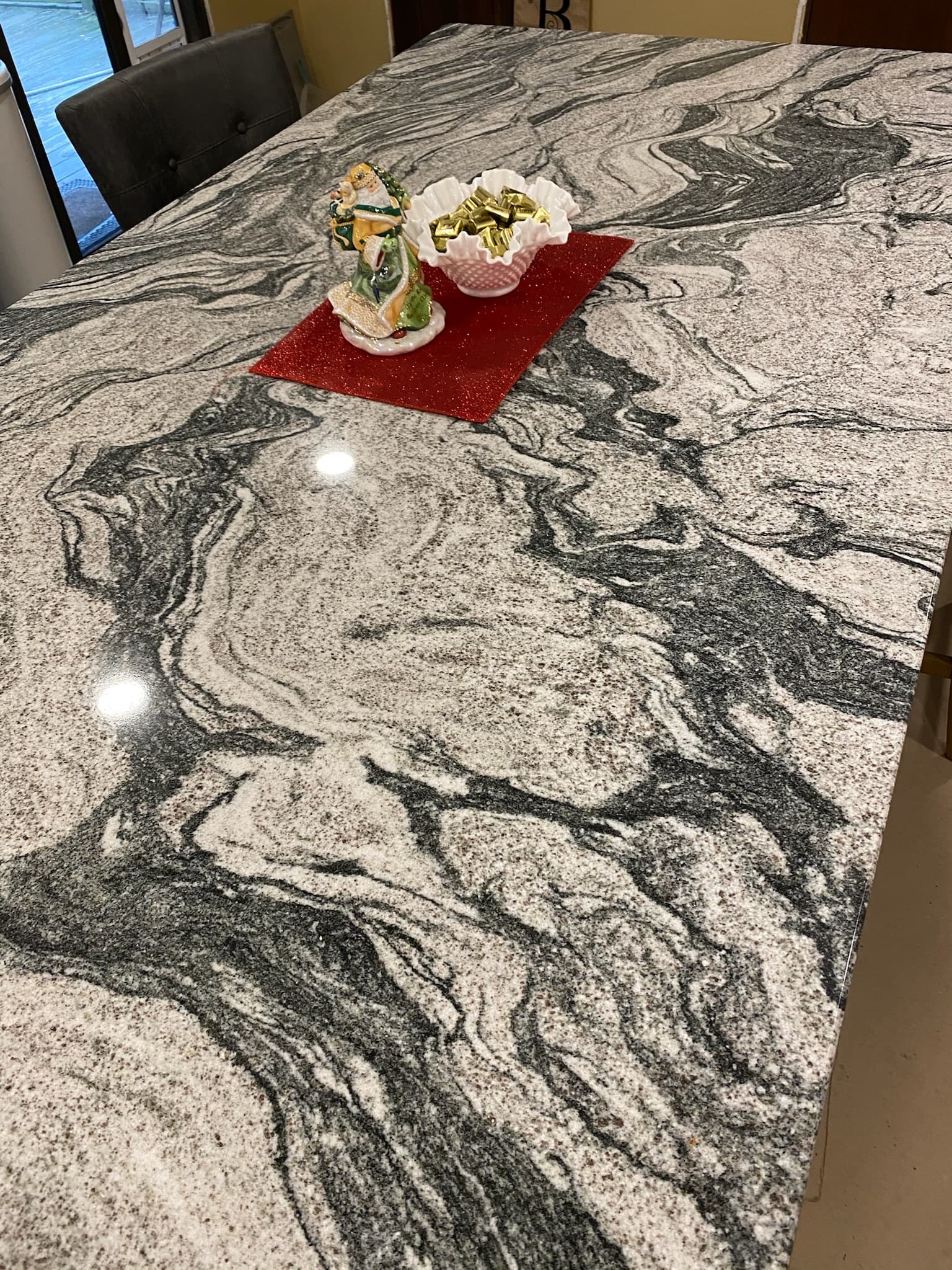 Close-up of a kitchen island with black, white, and gray granite countertop, featuring Christmas decor