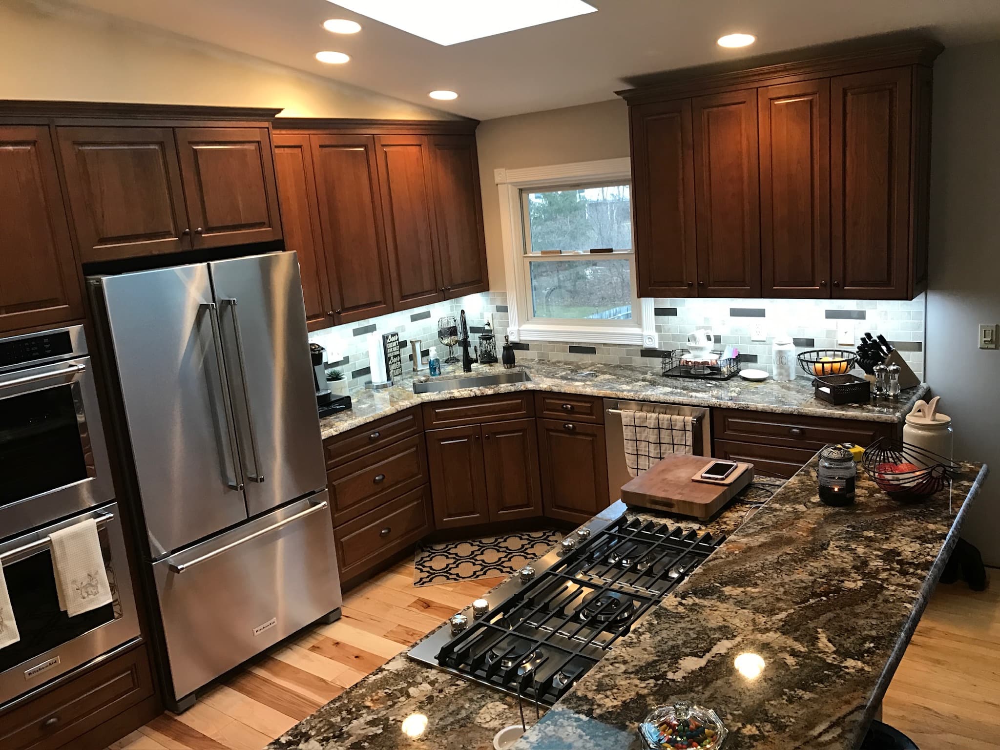 A transitional kitchen features dark wood raised-panel cabinets, granite countertops, and a large island with a gas cooktop
