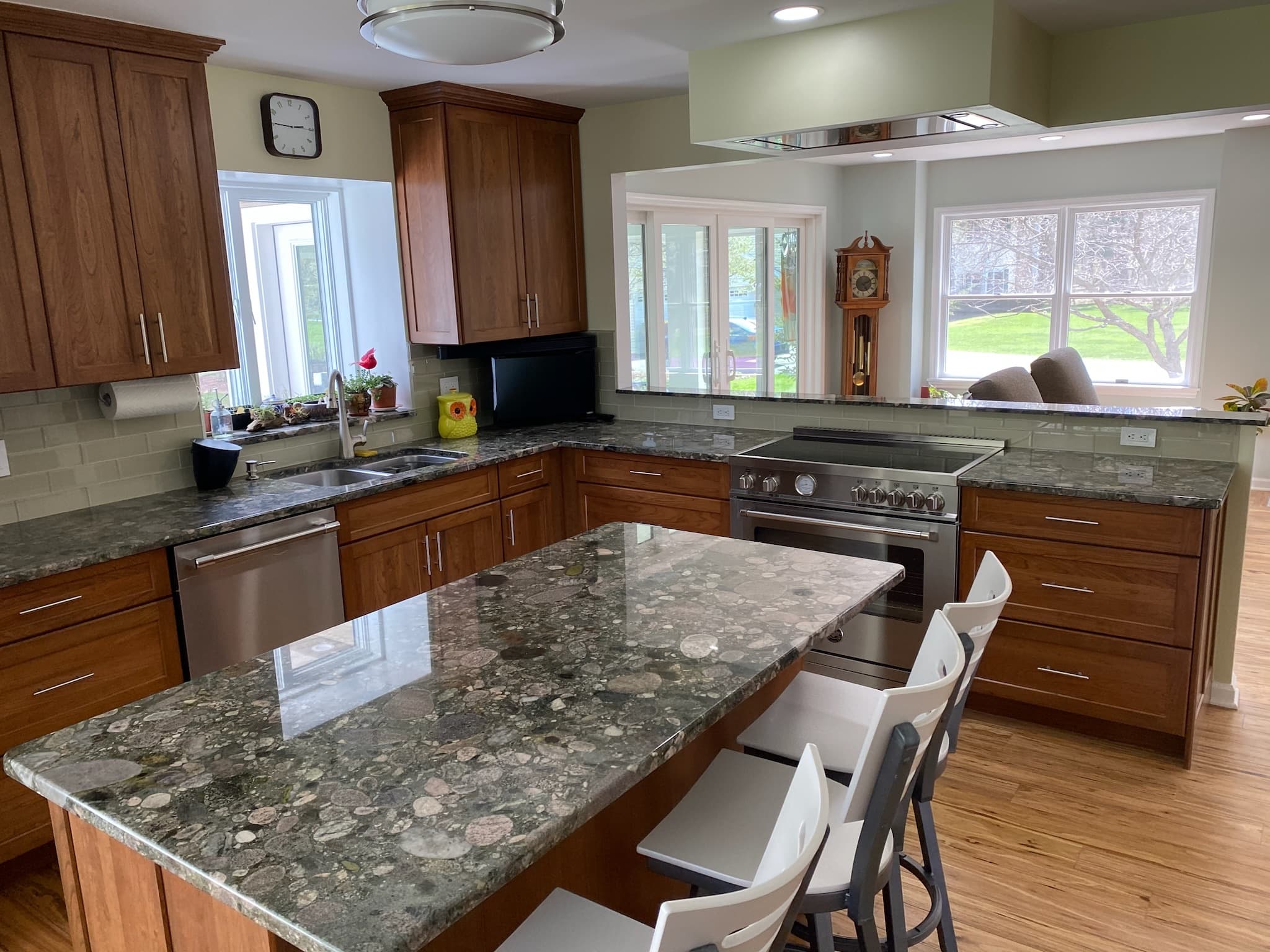 A transitional kitchen with medium wood cabinets, speckled granite countertops, and a large island with seating