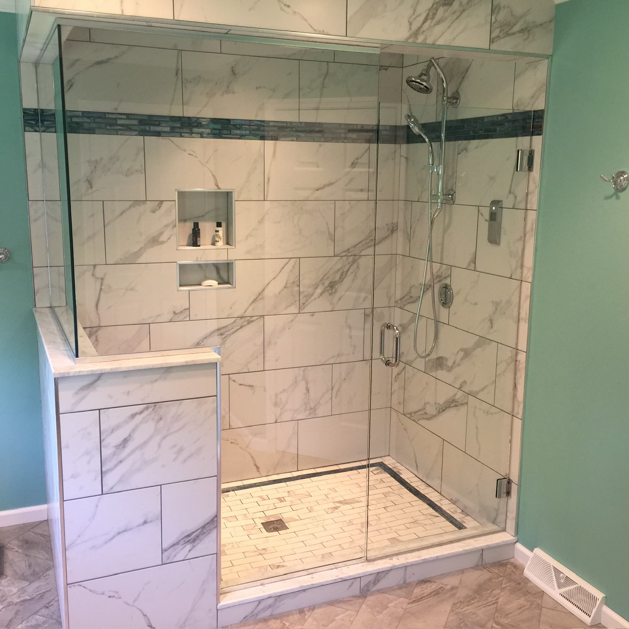 Spacious walk-in shower with white and grey marble-look tile, a blue glass mosaic accent stripe, and chrome fixtures