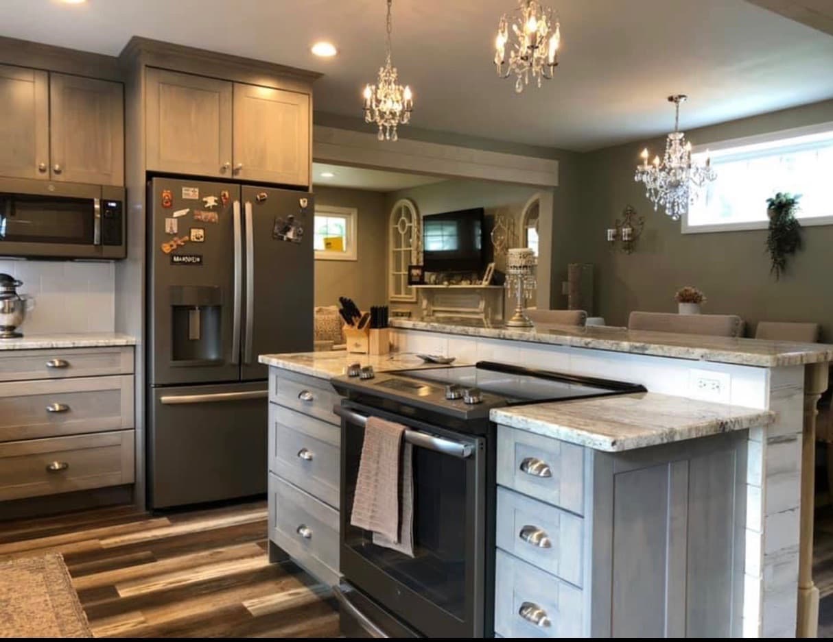 A transitional kitchen features gray recessed panel cabinets, granite countertops, and a peninsula with a breakfast bar