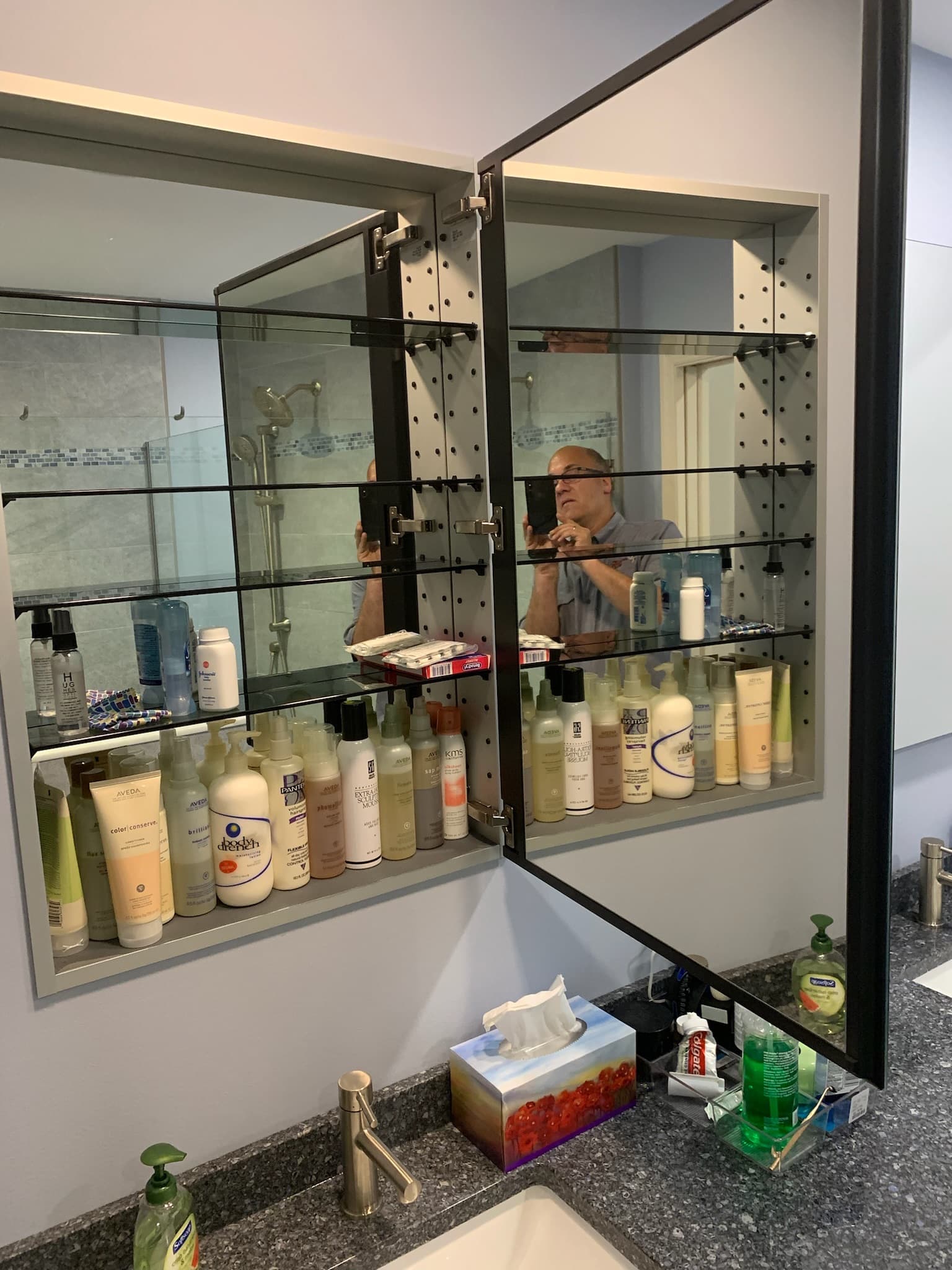 A bathroom vanity with a dark granite countertop, a brushed nickel faucet, and a large medicine cabinet with mirrored doors