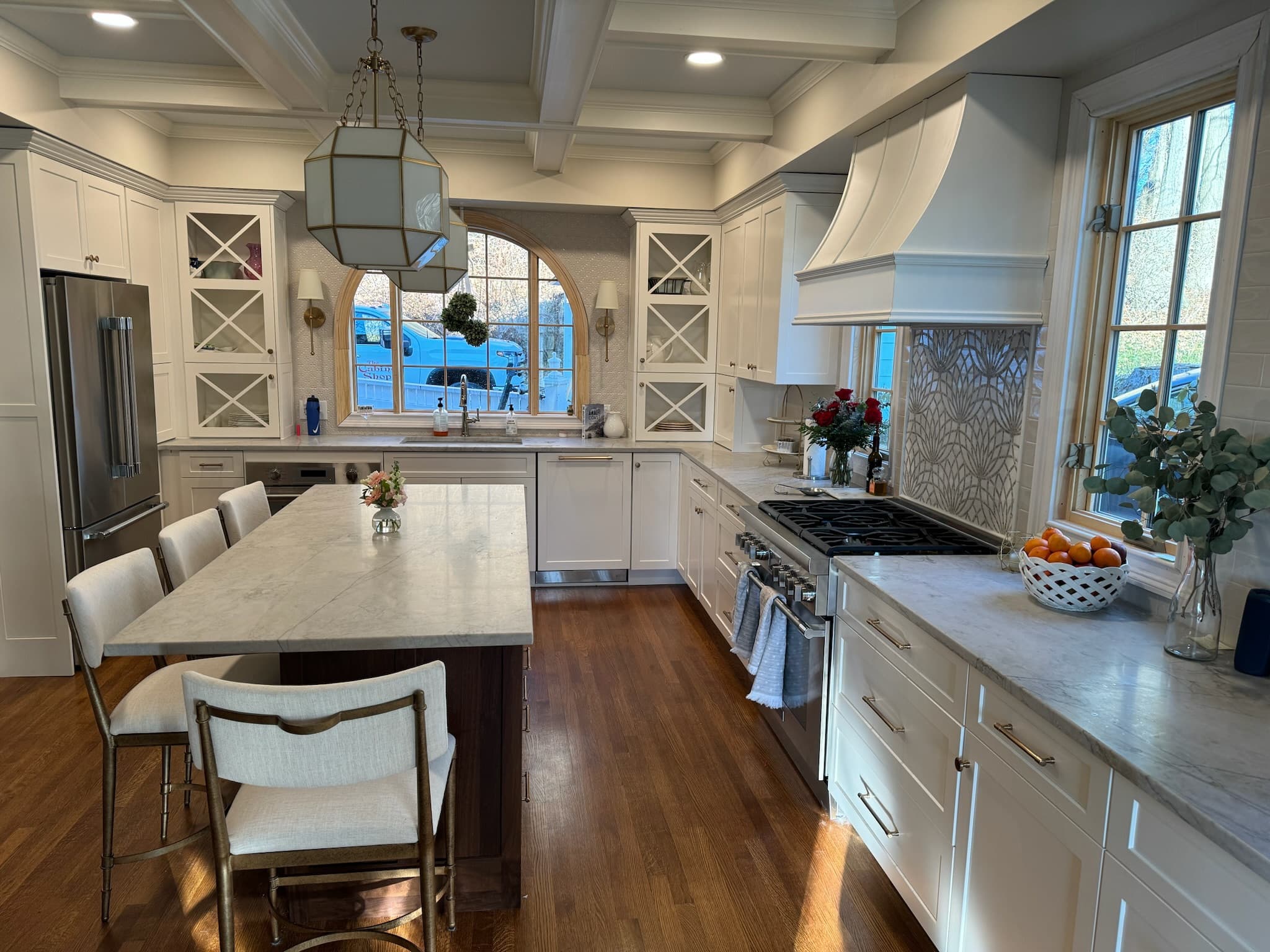 Wide view of the Saratoga Springs kitchen — white cabinetry, coffered ceiling, and island
