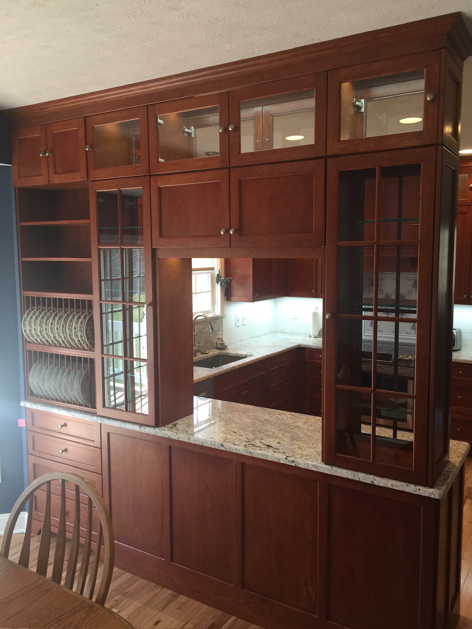 Traditional kitchen with medium wood raised panel cabinets, granite countertops, and a peninsula with glass-front cabinets