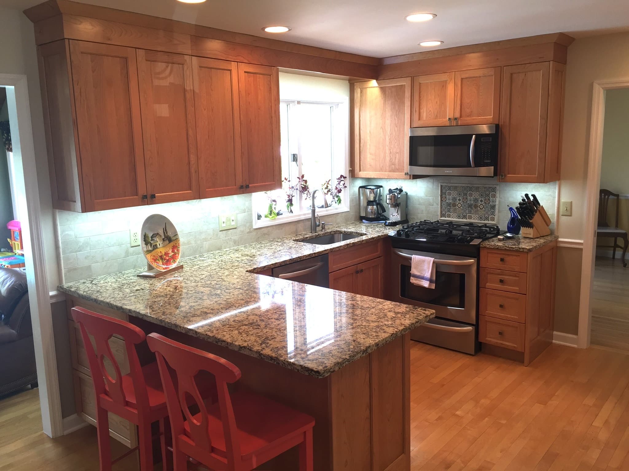 A transitional kitchen features medium wood cabinets, granite countertops, a peninsula with seating, and a stainless steel range and microwave